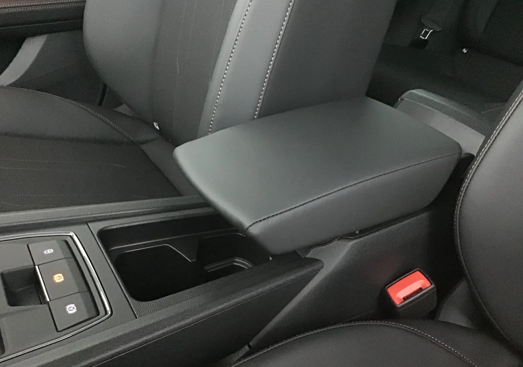 Gros plan sur l'accoudoir central en cuir noir et la console avec commandes électroniques dans l'habitacle d'une CUPRA Leon 2023.