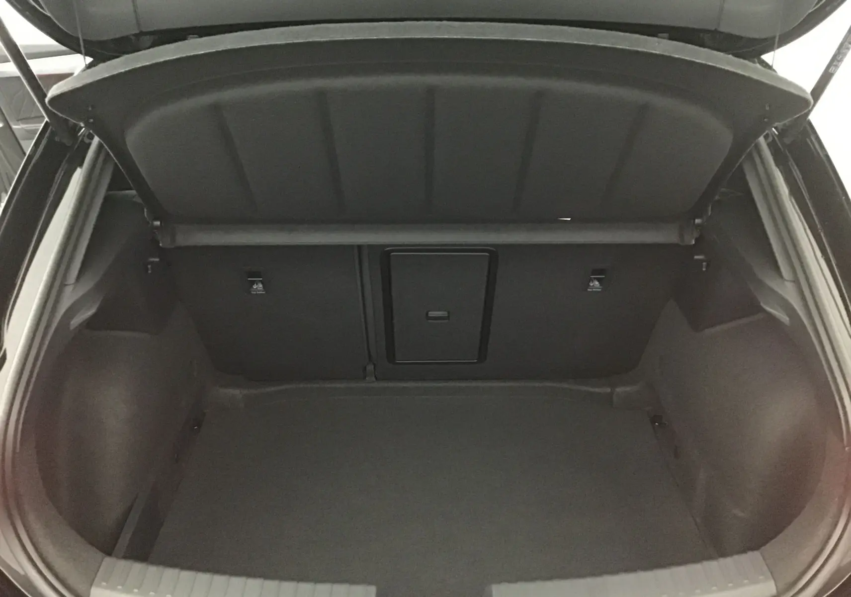 Coffre ouvert vu de l'arrière d'une CUPRA Leon noire 2023, montrant un espace de chargement vide et propre.