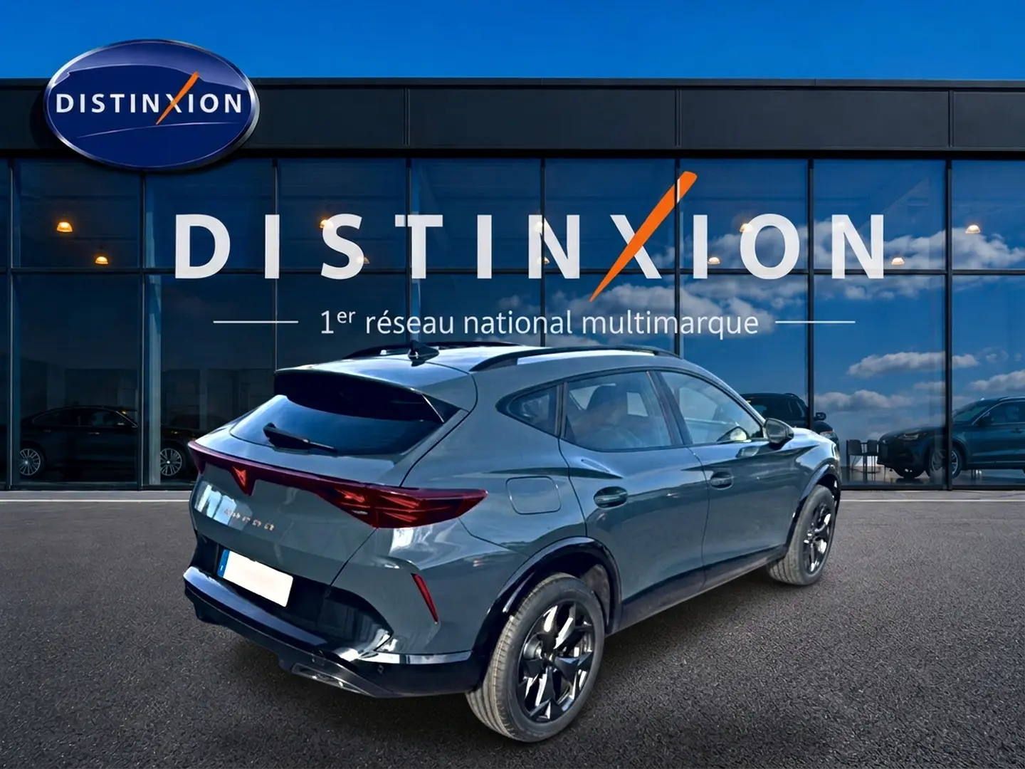 Vue 3/4 arrière droite d'un CUPRA Formentor bleu fjord avec jantes noires devant une vitrine Distinxion.