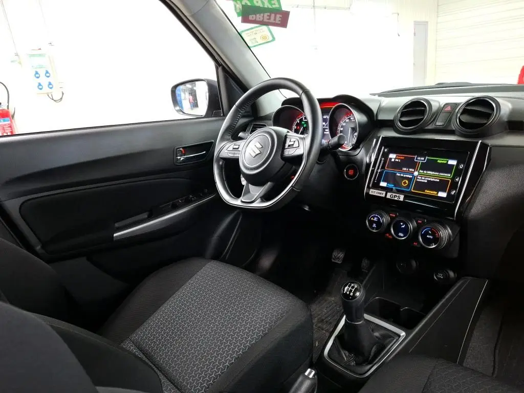 Vue intérieure côté conducteur de la Suzuki Swift grise 2023, avec volant multifonction, écran tactile et boîte manuelle.