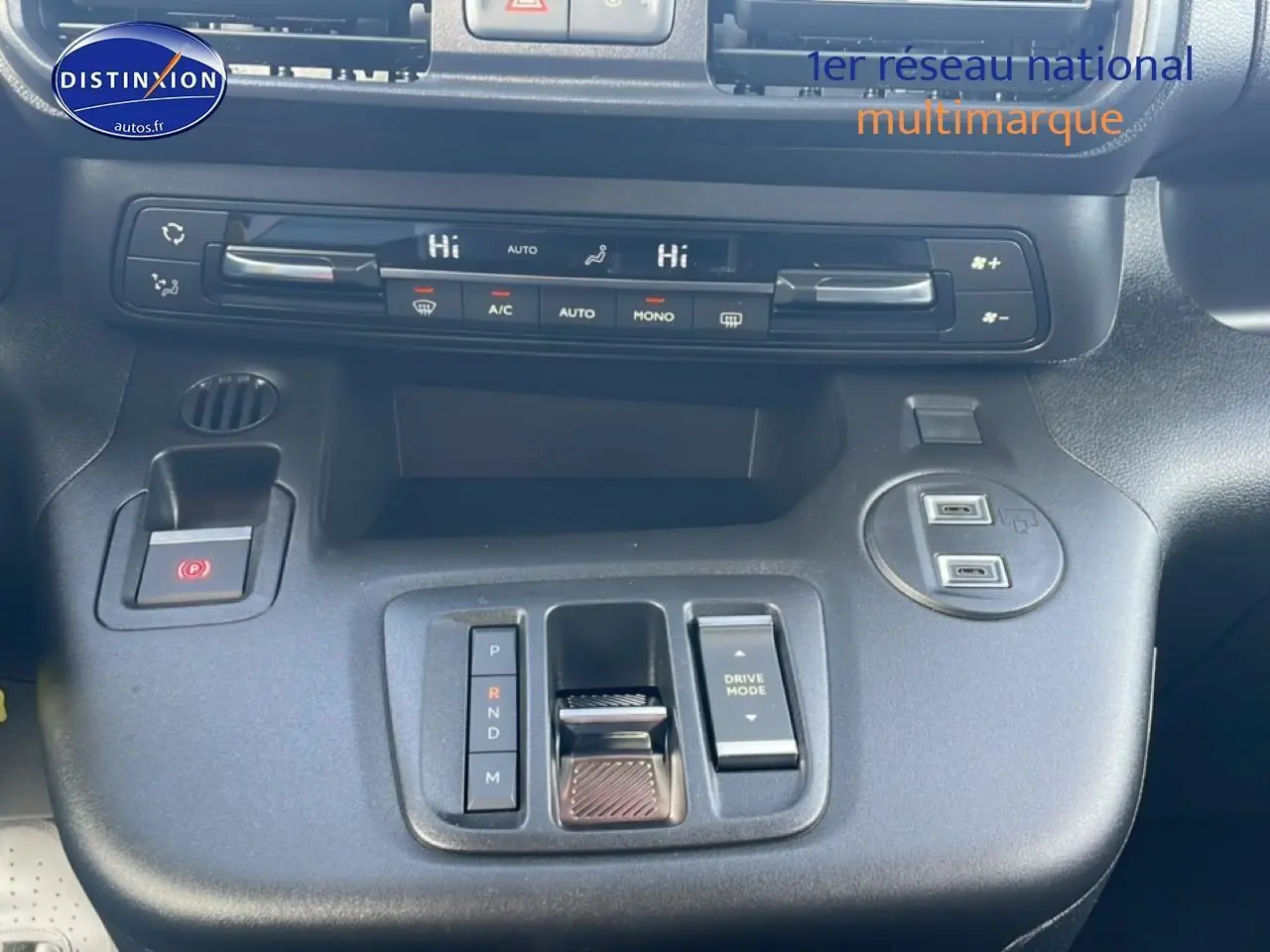 Vue intérieure centrée sur la console centrale du Citroën Berlingo gris, avec commandes clim et boîte auto compacte.