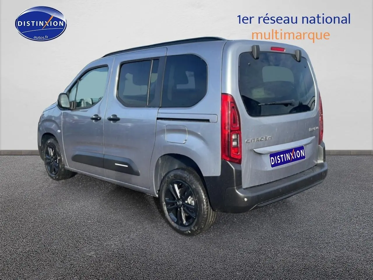 Vue 3/4 arrière droite d'un Citroën Berlingo gris artense avec jantes alu noires et barres de toit.