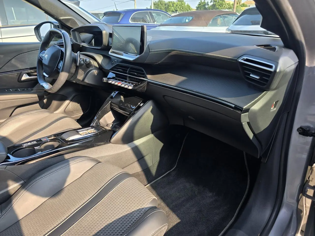 Vue intérieure côté passager de la Peugeot 208 grise 2023, tableau de bord carbone et écran tactile 10 pouces.