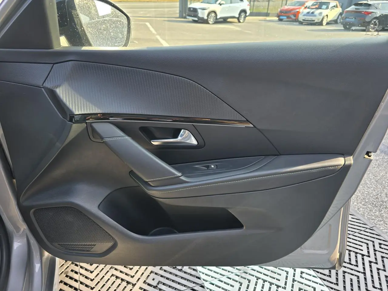 Vue côté gauche de la porte avant grise de la Peugeot 208 II avec habillage noir et insert décoratif texturé.