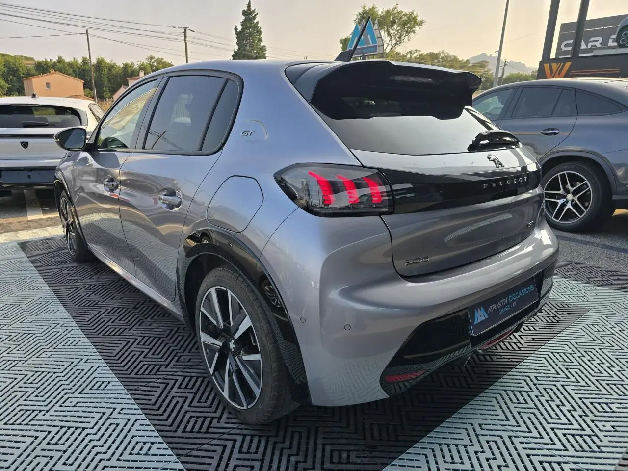 Vue 3/4 arrière droite d'une Peugeot 208 grise 2023 avec toit Black Diamond et jantes alliage 17 pouces Bronx.