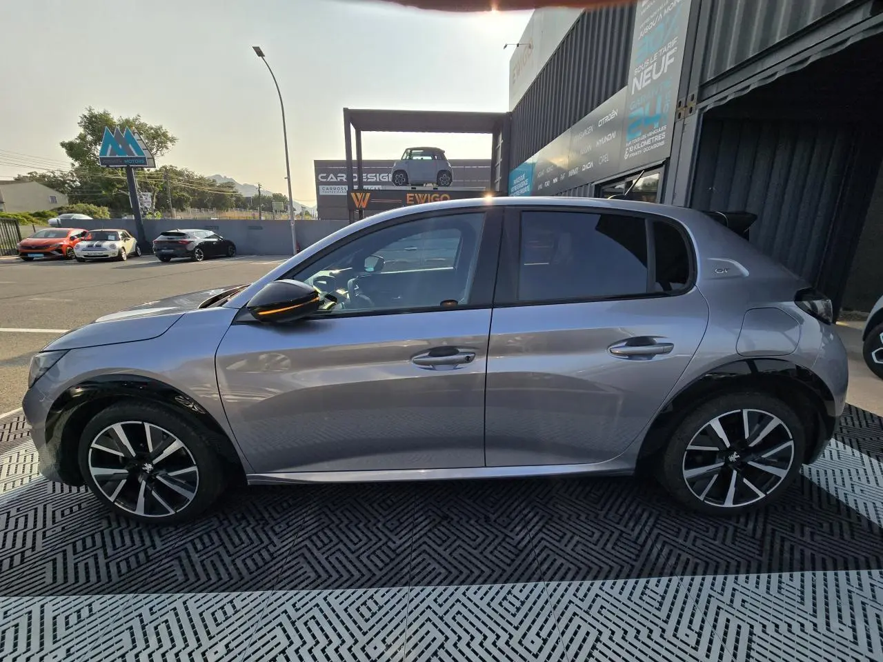 Profil côté gauche d'une Peugeot 208 grise 2023 avec jantes alliage 17'' et toit Black Diamond noir.