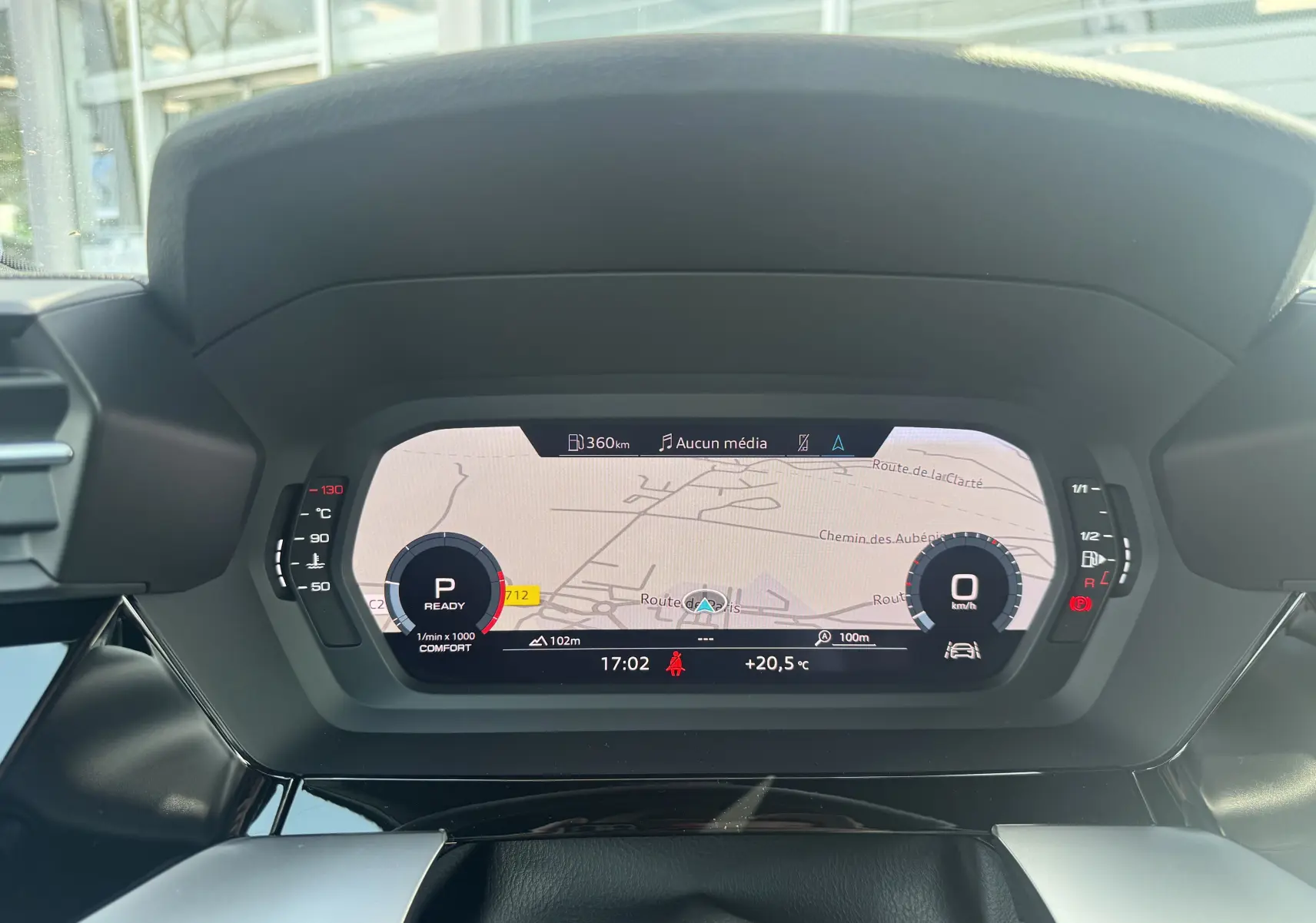 Vue rapprochée du tableau de bord numérique de l'Audi A3 Sportback gris, affichant la navigation et les indicateurs de vitesse et régime.