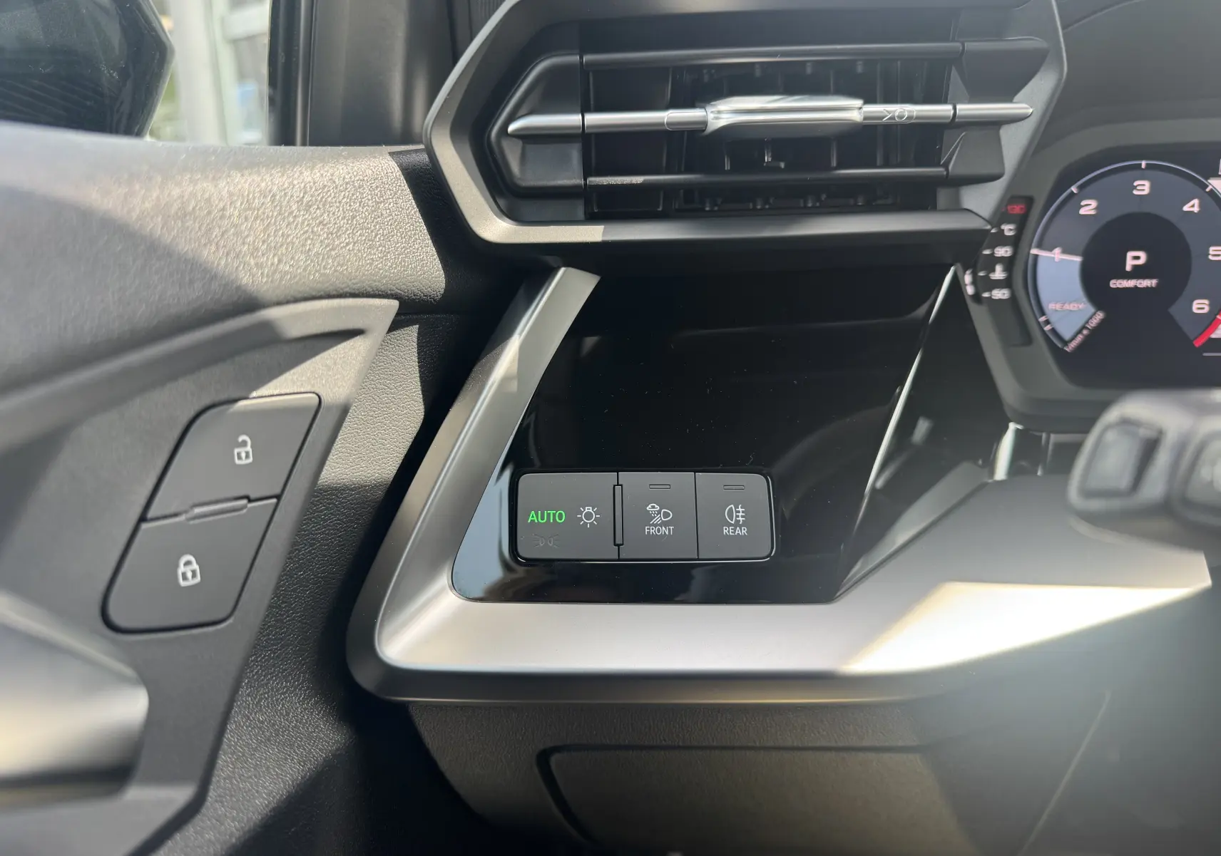 Détail intérieur côté gauche de l'Audi A3 Sportback gris 2023 montrant les commandes d'éclairage automatiques et la ventilation.