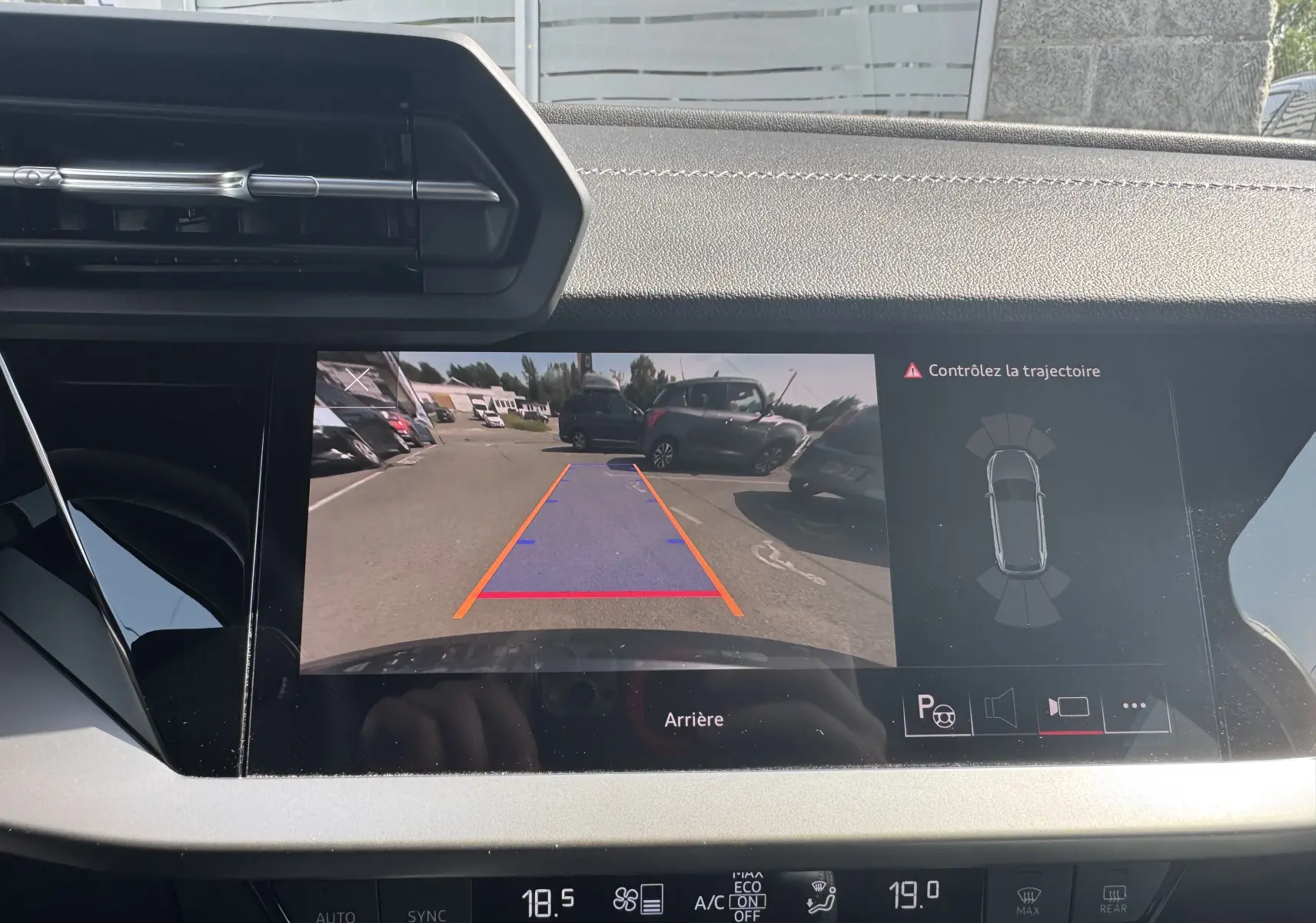 Vue intérieure sur l'écran de recul d'une Audi A3 Sportback gris 2023, avec affichage des lignes de guidage et capteurs.