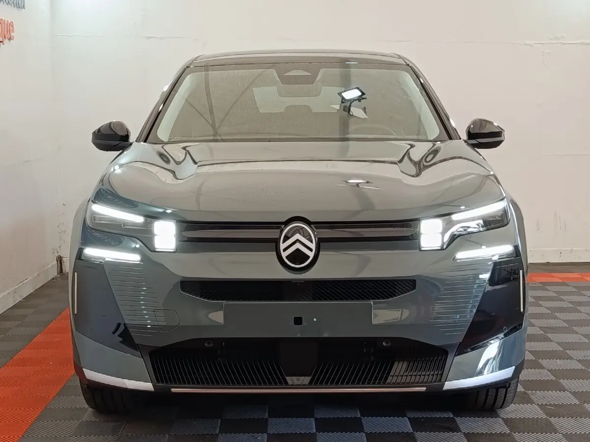 Vue avant frontale d'une Citroën C5 hybride 2026 vert avec phares LED et logo Citroën central lumineux.