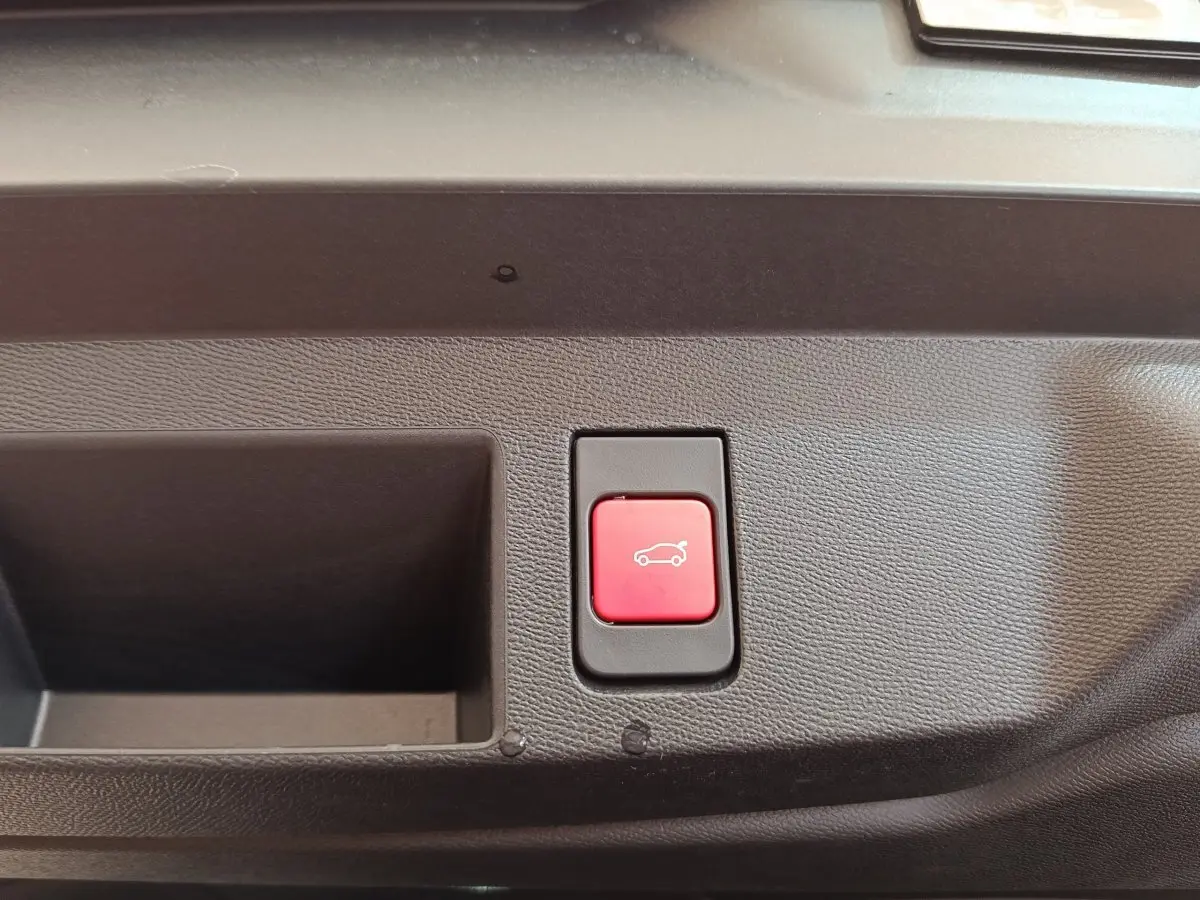 Bouton rouge d'ouverture électrique du coffre sur panneau intérieur d'une Citroën C5 Hybride 2026.