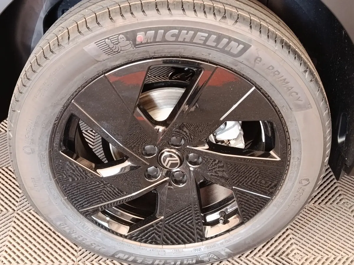 Gros plan sur la jante noire brillante avec logo Citroën, montée sur un pneu Michelin e.Primacy.