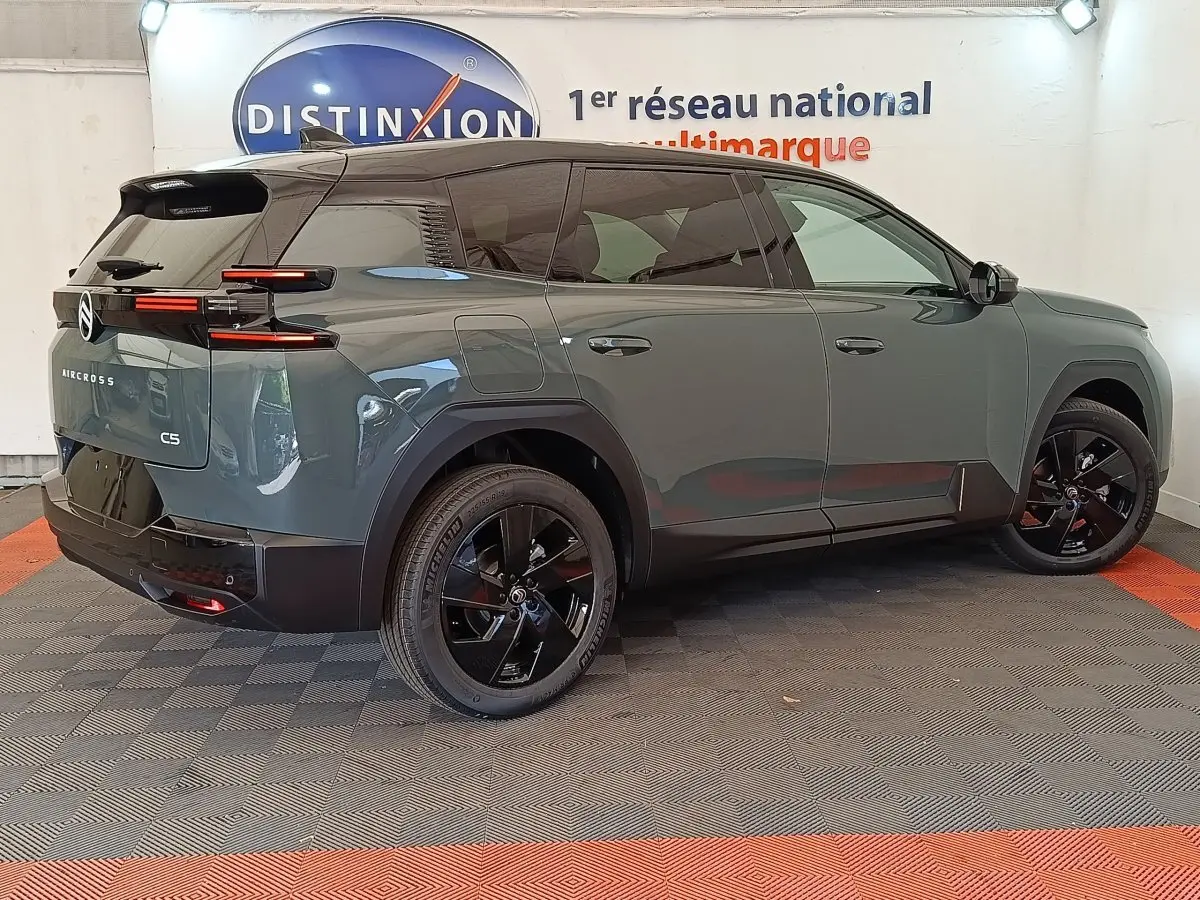 Vue 3/4 arrière droite d'une Citroën C5 Aircross hybride 2026 vert avec jantes noires et toit noir brillant.