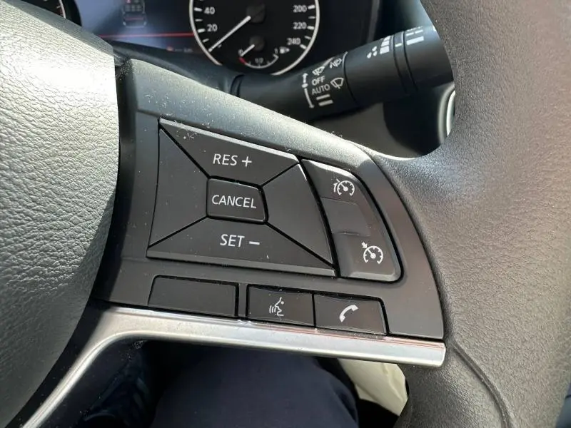Gros plan sur les commandes multifonctions du volant côté droit du Nissan Juke 2025 blanc nacré.