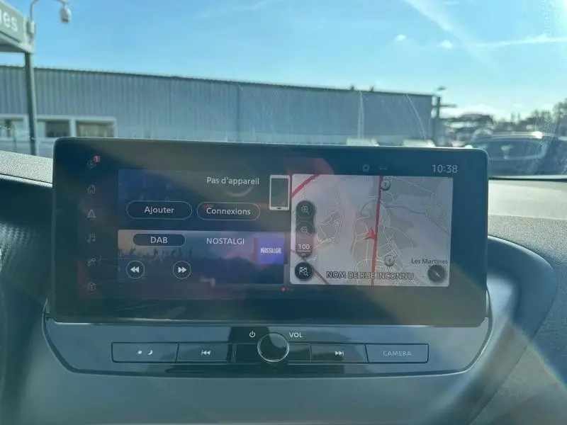 Écran tactile central du tableau de bord du Nissan Juke blanc nacré, affichant navigation et radio.