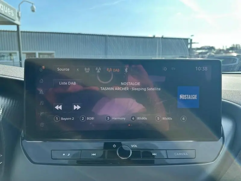 Écran tactile central du Nissan Juke 2025 affichant la radio DAB avec commandes audio et bouton caméra.