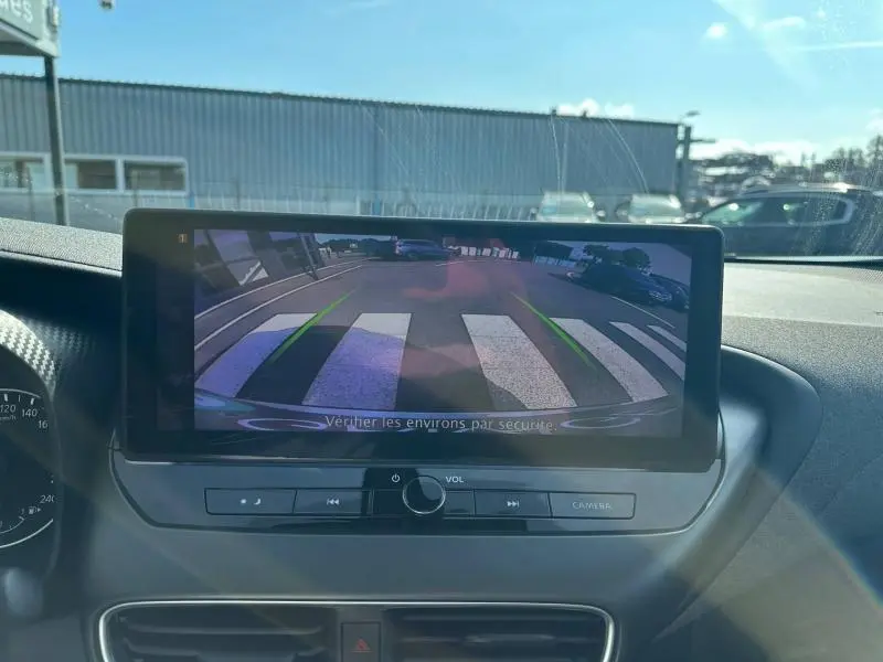 Écran tactile intérieur montrant la caméra de recul du Nissan Juke blanc nacré, vue du tableau de bord.