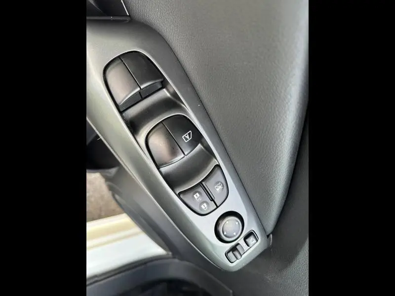 Gros plan sur les commandes de vitres et rétroviseurs côté conducteur du Nissan Juke 2025, intérieur noir.