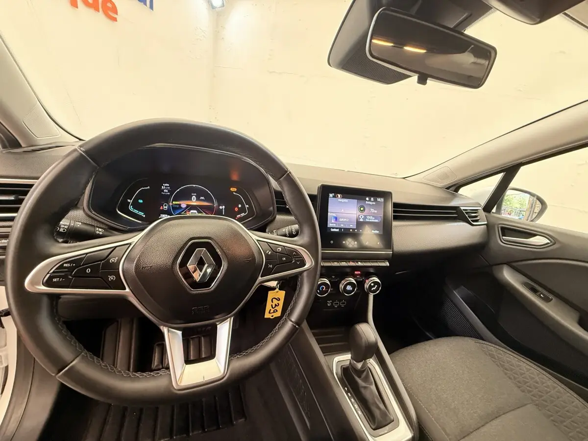 Vue intérieure avant de la Renault Clio Business E-Tech hybride blanche 2022, volant cuir multifonctions et écran tactile central.
