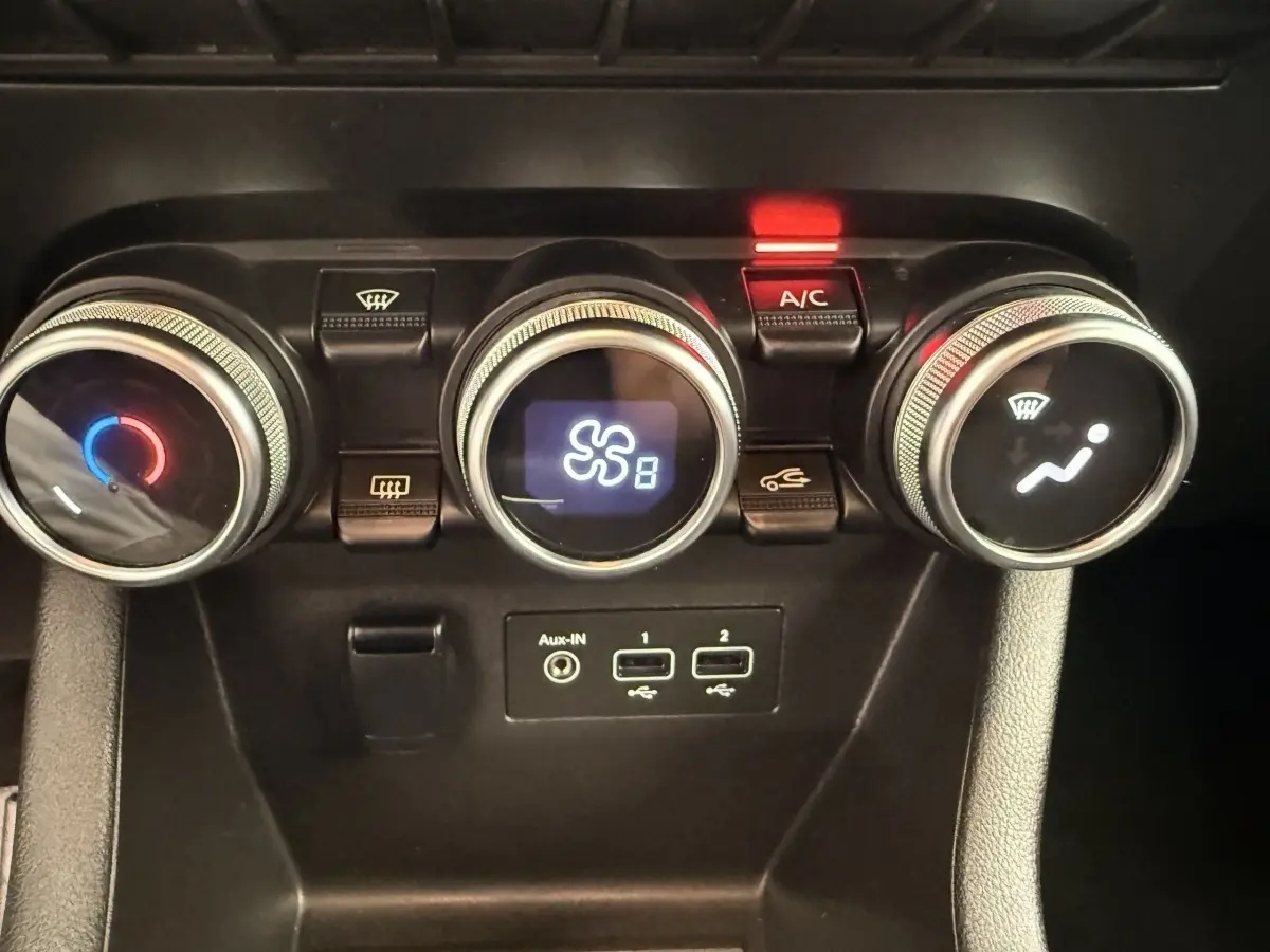 Vue rapprochée des commandes de climatisation avec trois molettes et ports USB dans une Renault Clio blanche hybride 2022.
