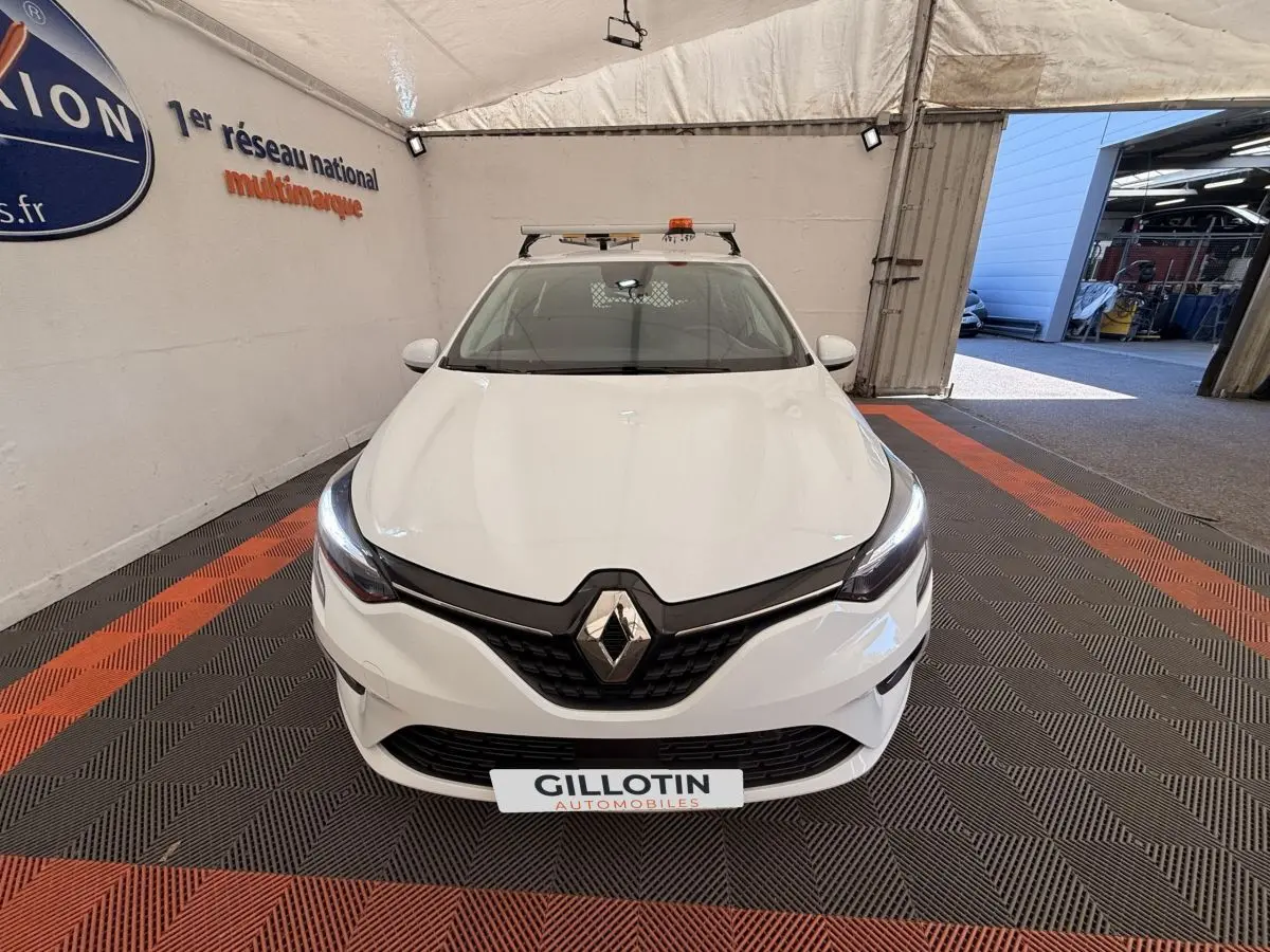 Vue avant d'une Renault Clio Business E-Tech hybride blanche, avec phares LED allumés dans un showroom.