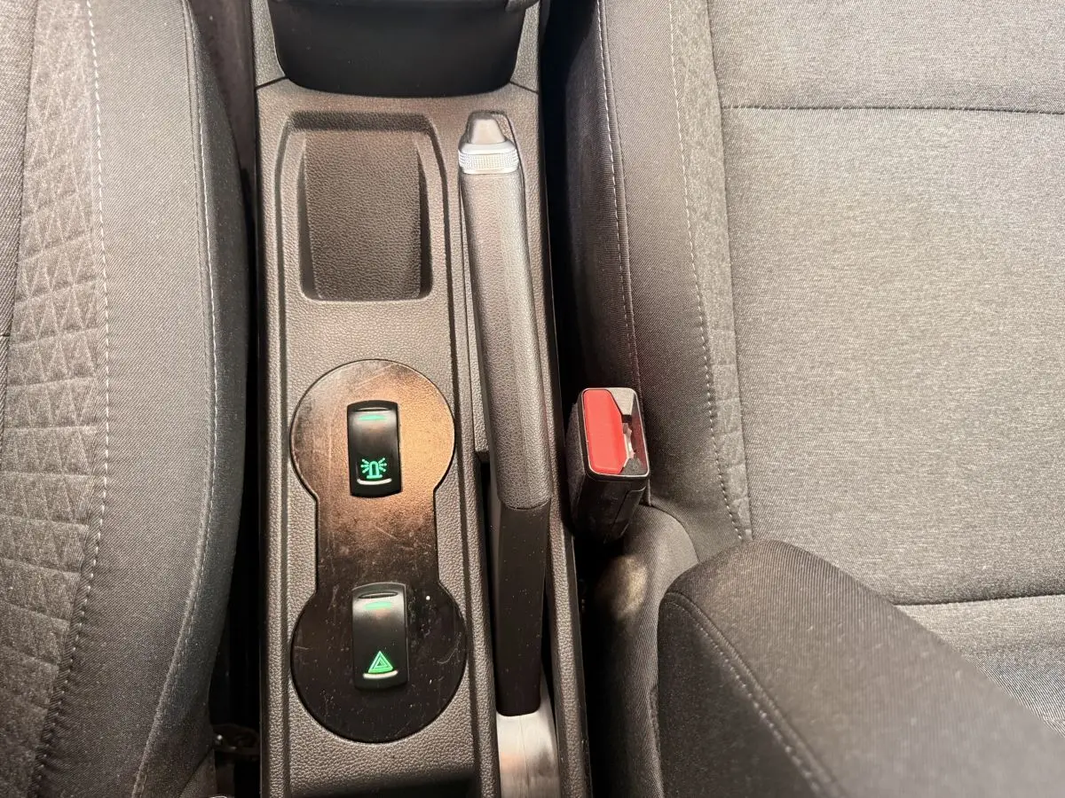 Vue rapprochée de la console centrale intérieure de la Renault Clio blanche, montrant frein à main et boutons de commande.