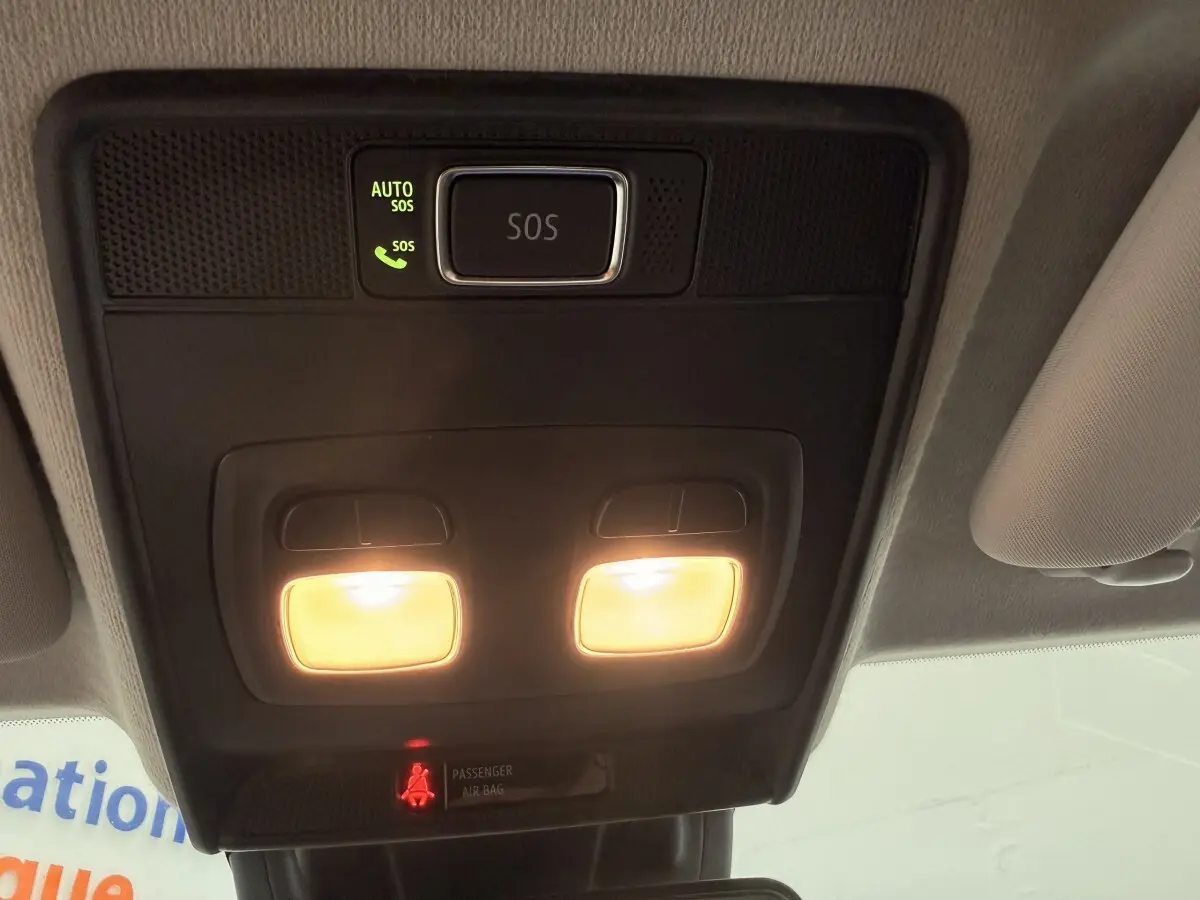 Vue intérieure en plongée sur le plafonnier noir avec éclairage et bouton SOS allumé dans une Renault Clio blanche.