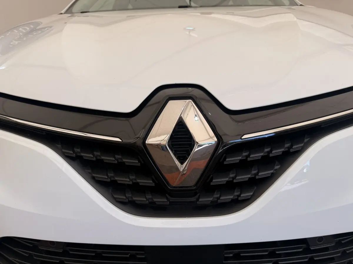 Gros plan sur la calandre avant blanche d'une Renault Clio Business E-Tech hybride 2022 avec logo chromé central.