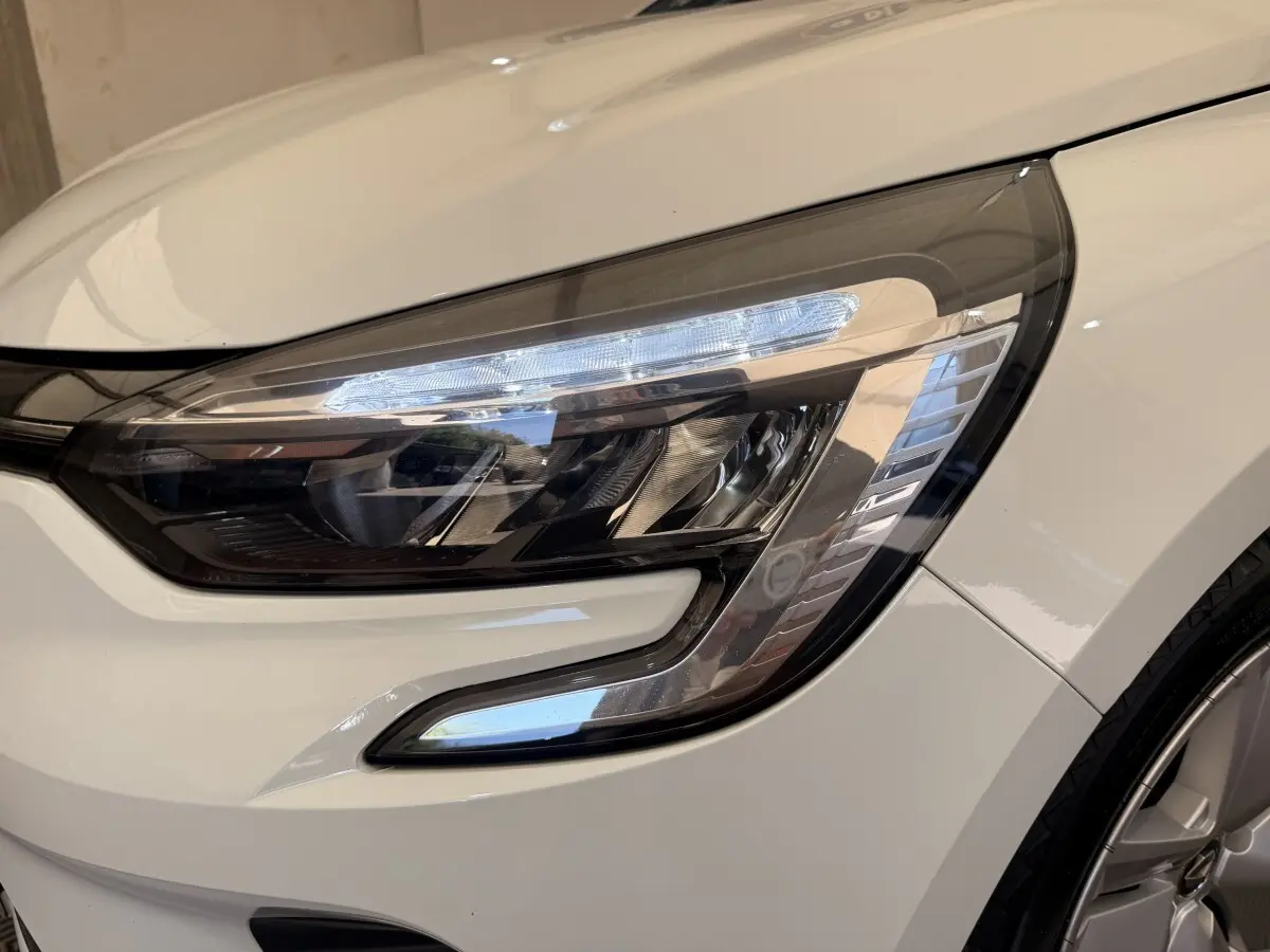 Gros plan sur le phare avant droit LED d'une Renault Clio Business E-Tech hybride blanche de 2022.