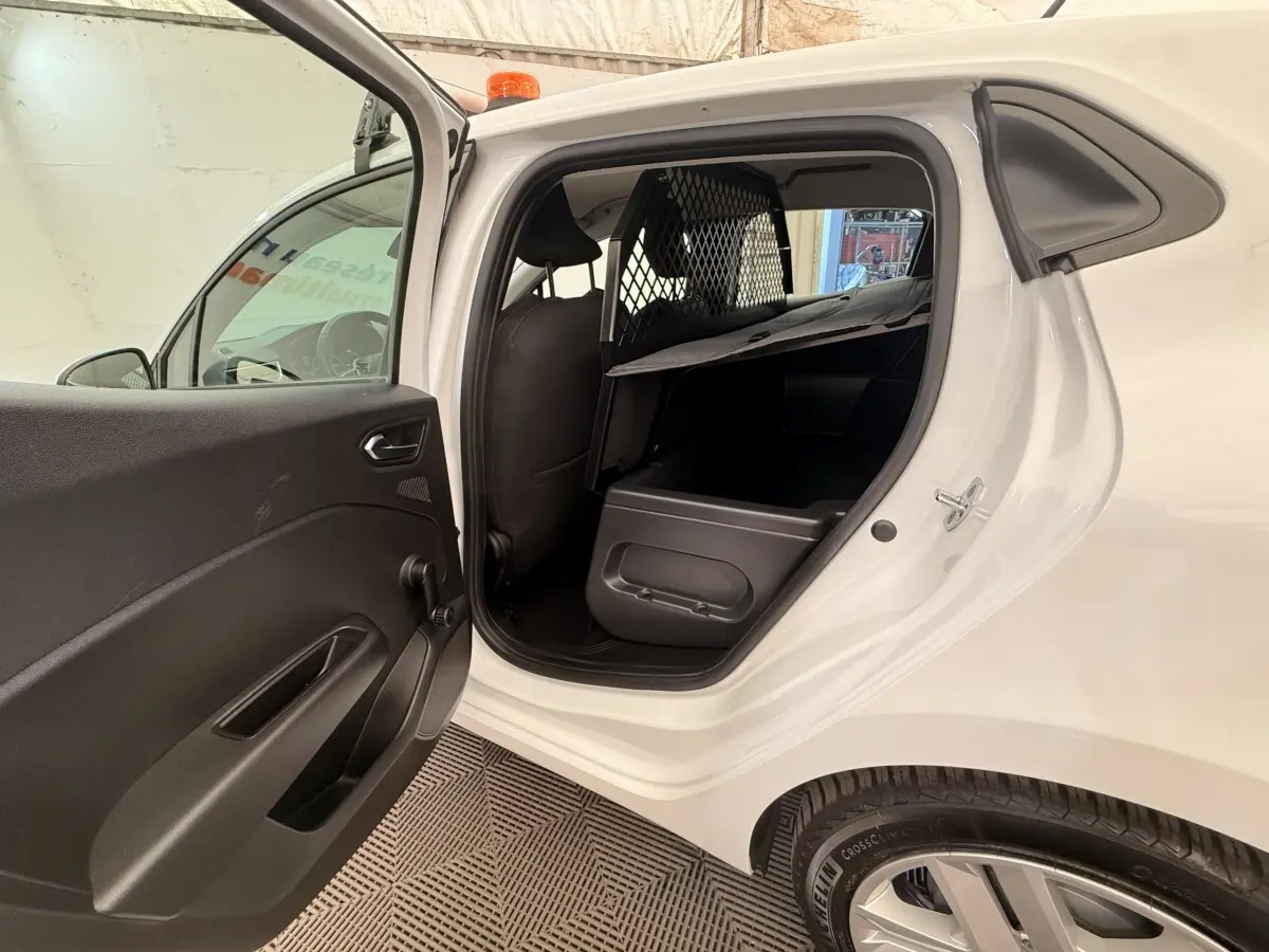 Vue côté gauche arrière d'une Renault Clio blanche 2022 avec porte ouverte, montrant l'intérieur et la grille de séparation.