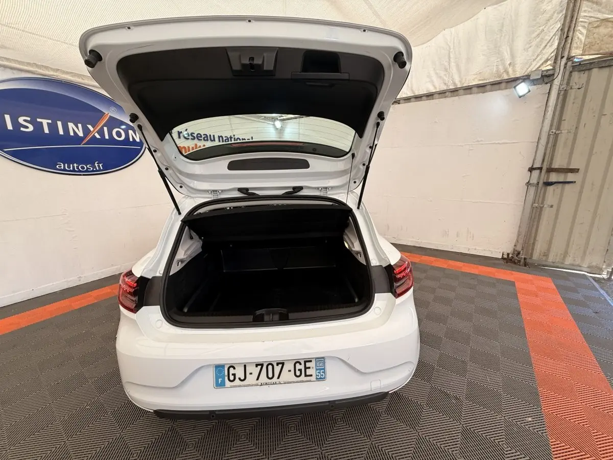 Vue arrière d'une Renault Clio Business E-Tech hybride blanche 2022 avec coffre ouvert dans un garage.