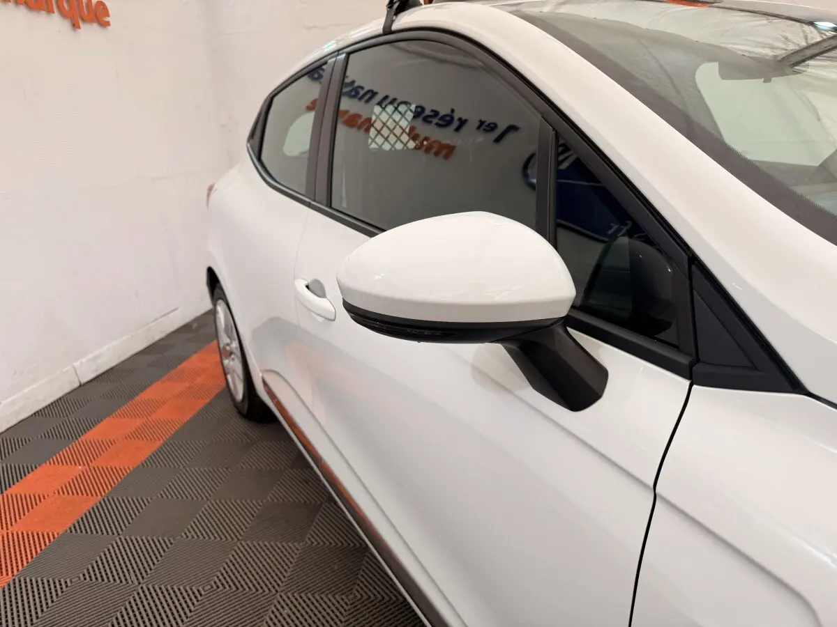 Vue rapprochée côté gauche d'une Renault Clio Business E-Tech hybride blanche, mettant en valeur le rétroviseur et la portière.