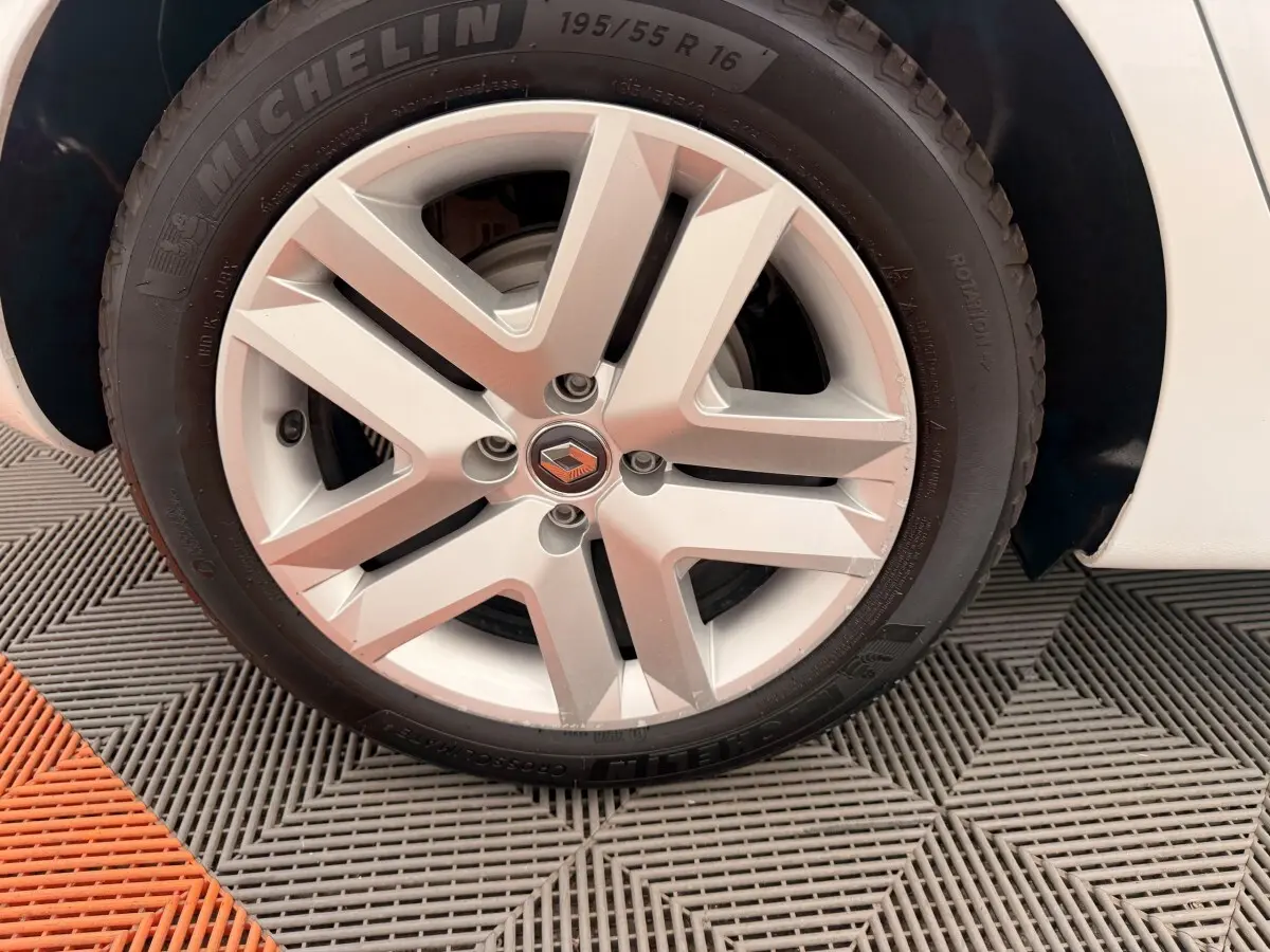 Gros plan sur la roue avant droite d'une Renault Clio blanche, mettant en valeur la jante alliage et le pneu Michelin.