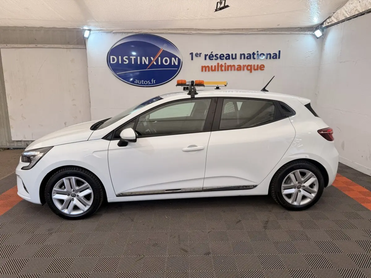 Profil droit d'une Renault Clio blanche hybride 2022, avec jantes alliage et toit équipé d'une rampe lumineuse orange.