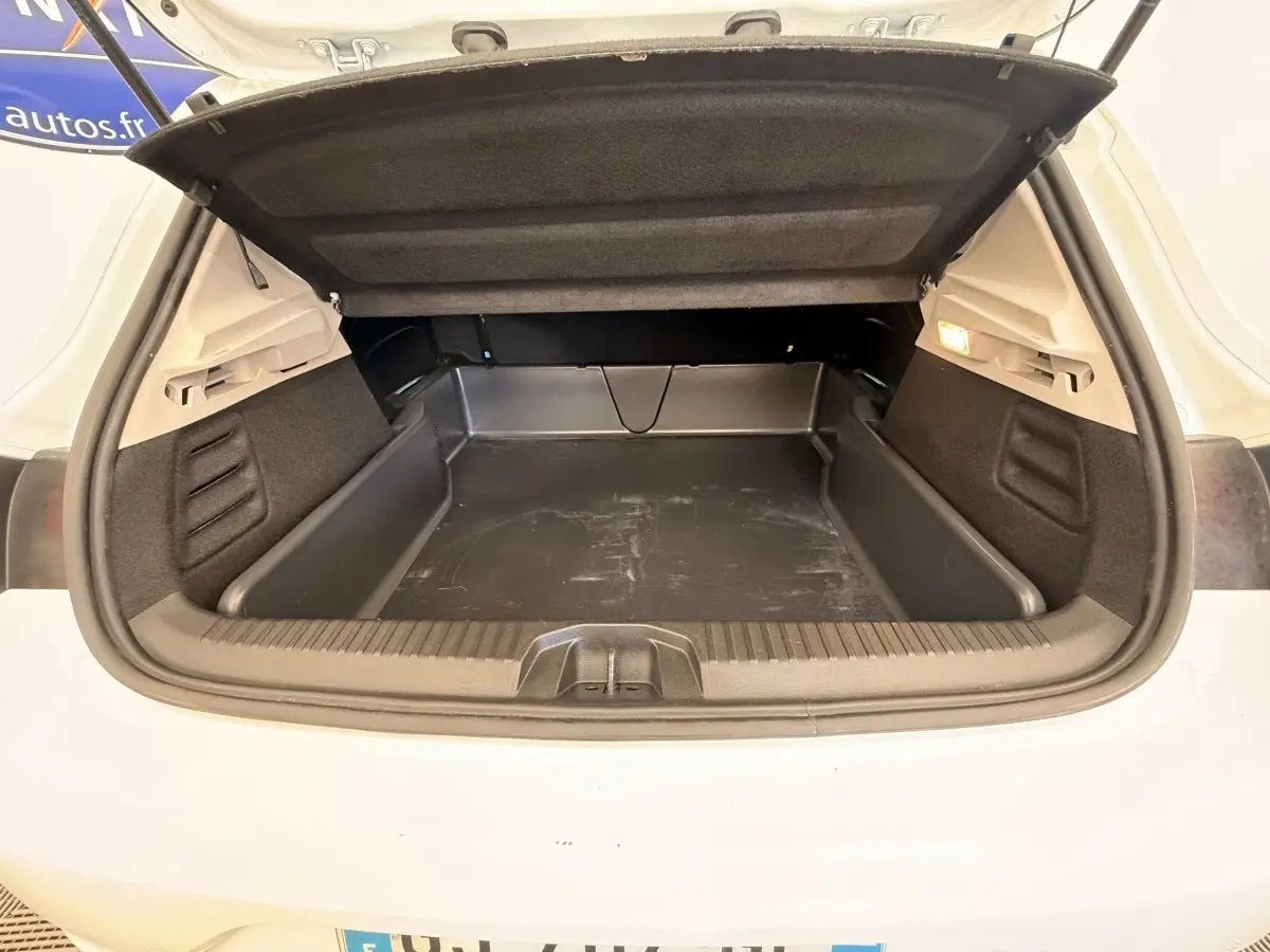 Coffre ouvert vu de l'arrière d'une Renault Clio Business E-Tech hybride blanche, avec tapis de protection noir.