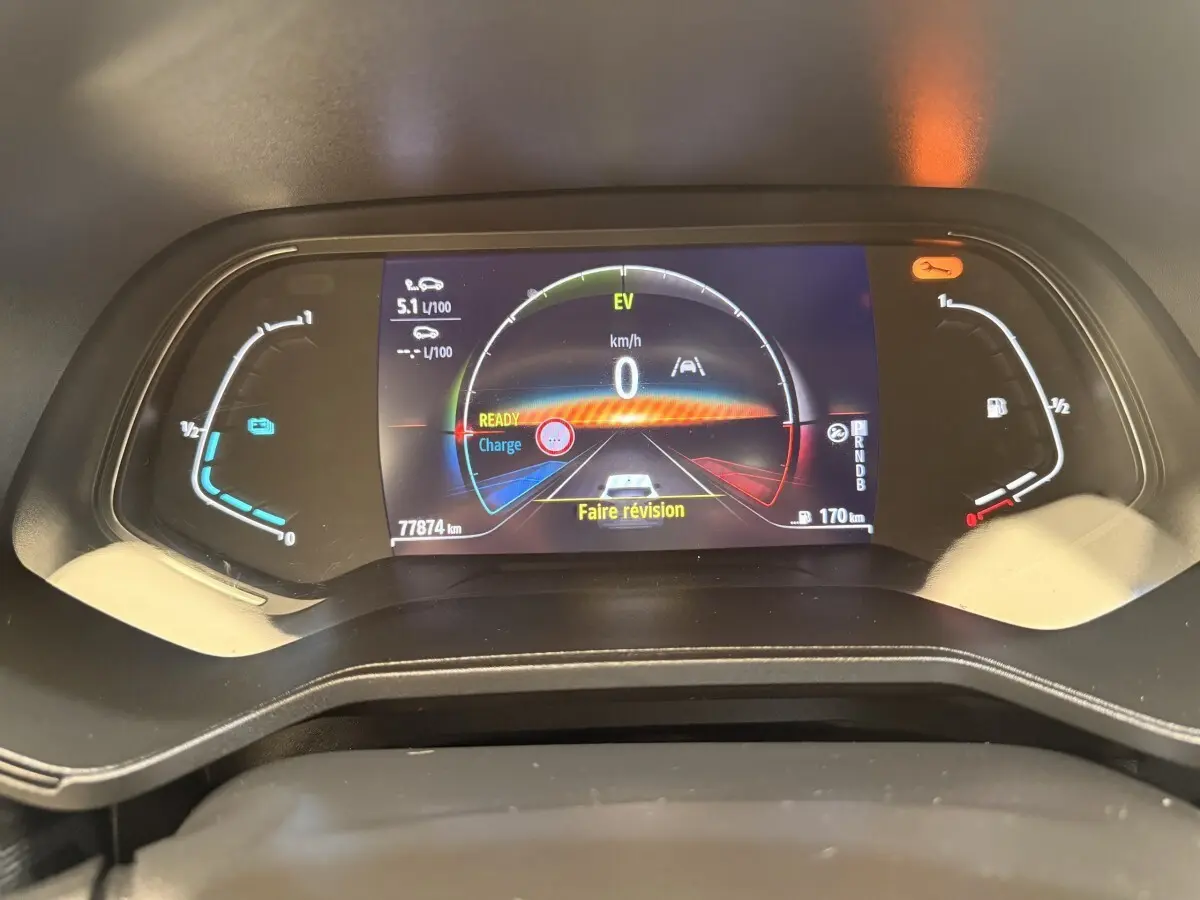 Gros plan sur le combiné d'instruments numérique de la Renault Clio Business E-Tech hybride blanc, affichant 0 km/h et message "Faire révision".