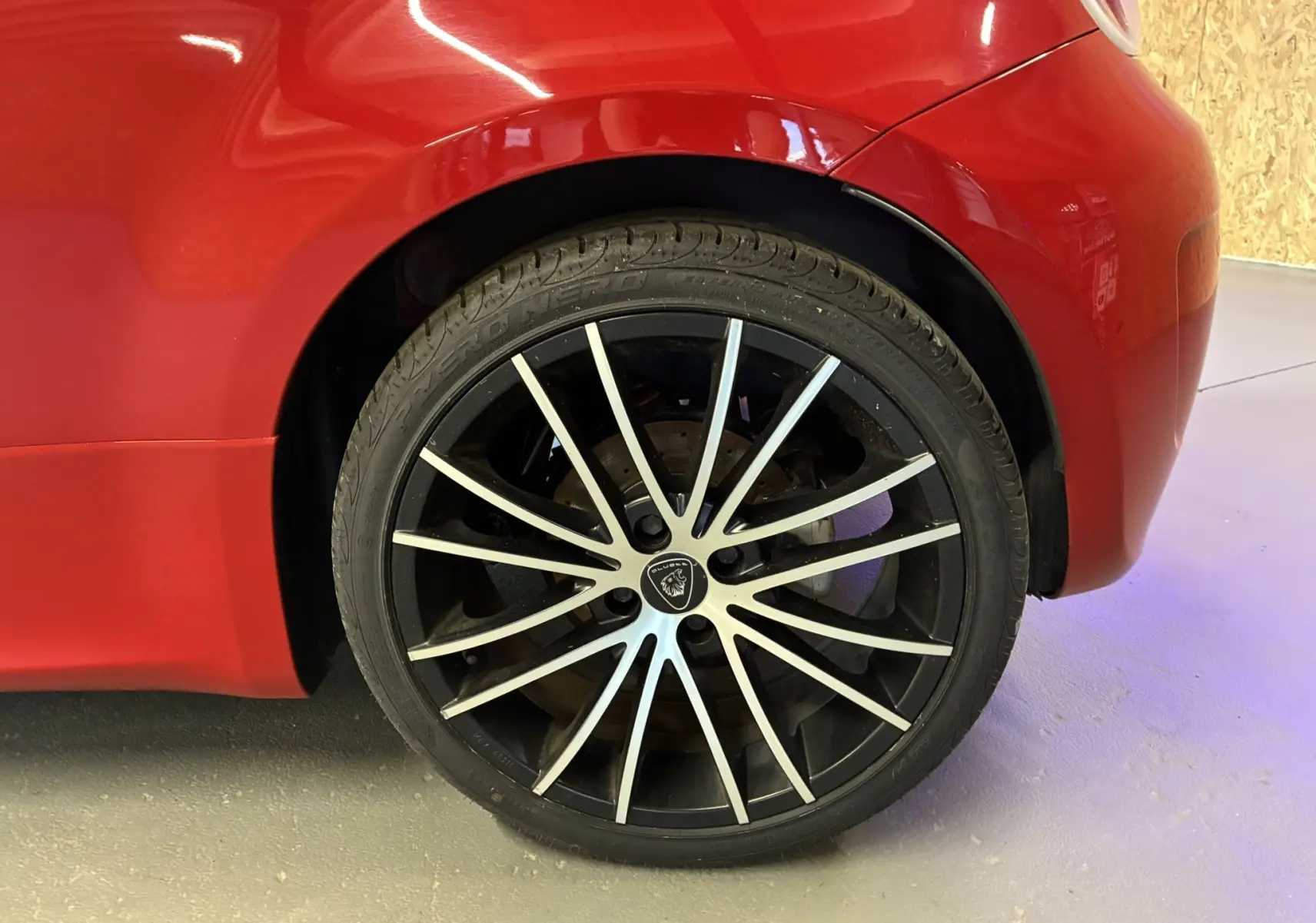Gros plan sur la roue arrière droite d'une ABARTH 500 rouge 2016, avec jante noire à rayons argentés distinctifs.