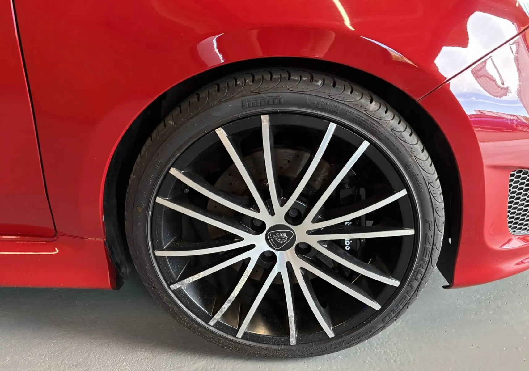 Gros plan sur la roue avant droite rouge d'une ABARTH 500 595 Competizione avec jante noire à rayons argentés.