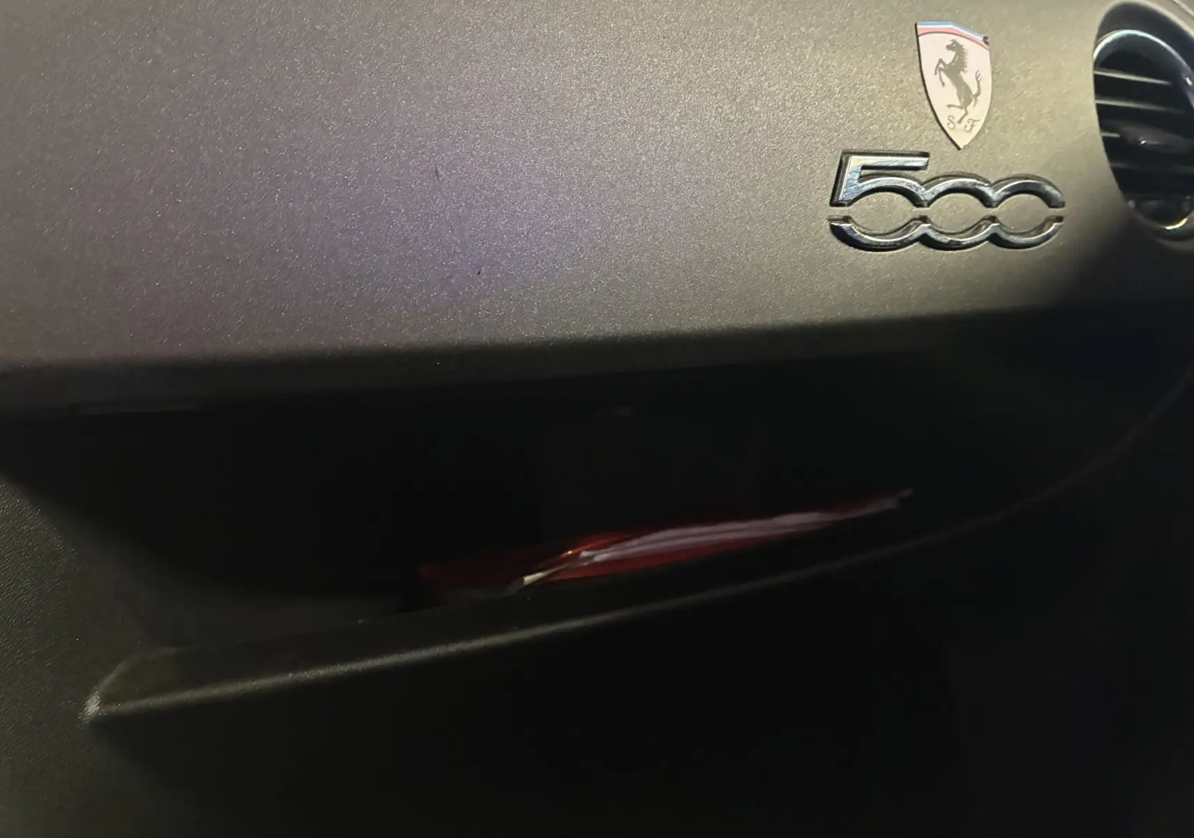 Détail de la planche de bord côté passager de l'Abarth 500 rouge 2016 avec logo 500 et écusson Abarth.