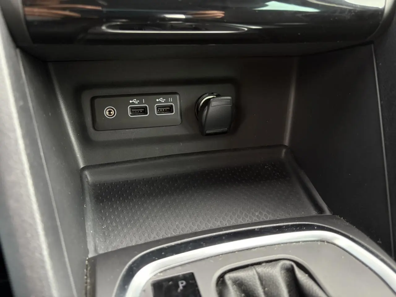 Gros plan sur la console centrale de la Renault Mégane Break 2024 avec ports USB et prise 12V, finition noire.
