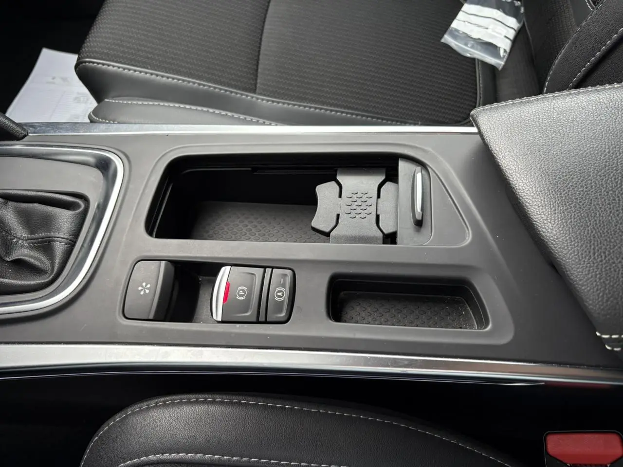 Vue rapprochée de la console centrale noire du Renault Mégane Break 2024 avec commandes de frein à main électrique et rangement.