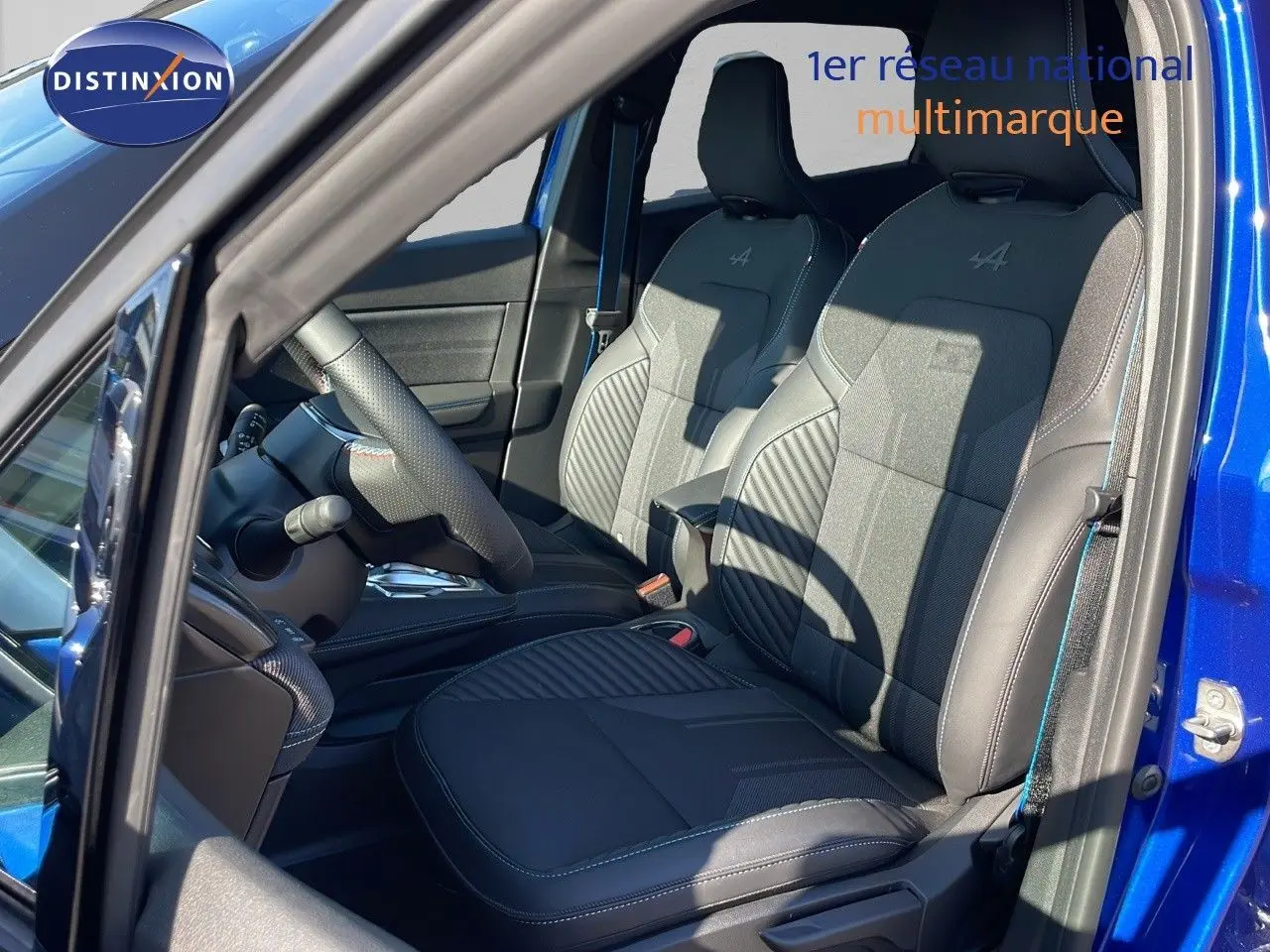 Vue intérieure côté conducteur du Renault Captur E-Tech hybride 2025 avec sièges noirs Alpine et portière bleu iron metal ouverte.