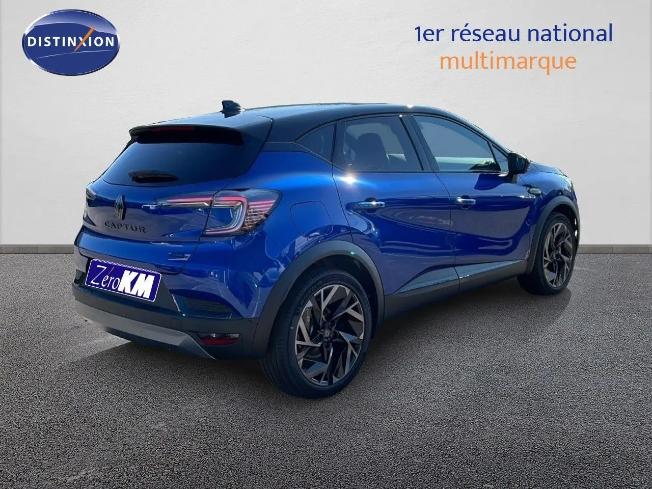 Renault Captur E-Tech hybride bleu Iron Metal avec toit noir, vue 3/4 arrière côté droit sur sol gris.