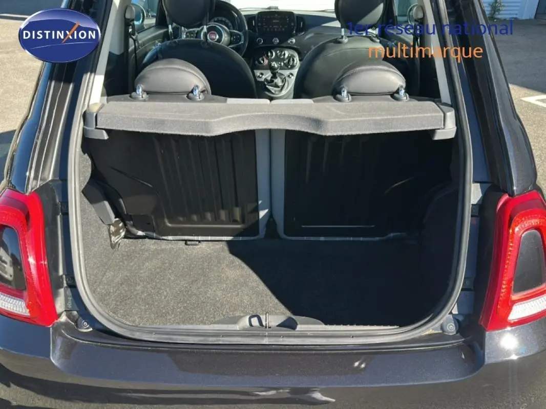 Vue arrière du coffre ouvert d'une FIAT 500 noire série 4, montrant l'intérieur et le tableau de bord.