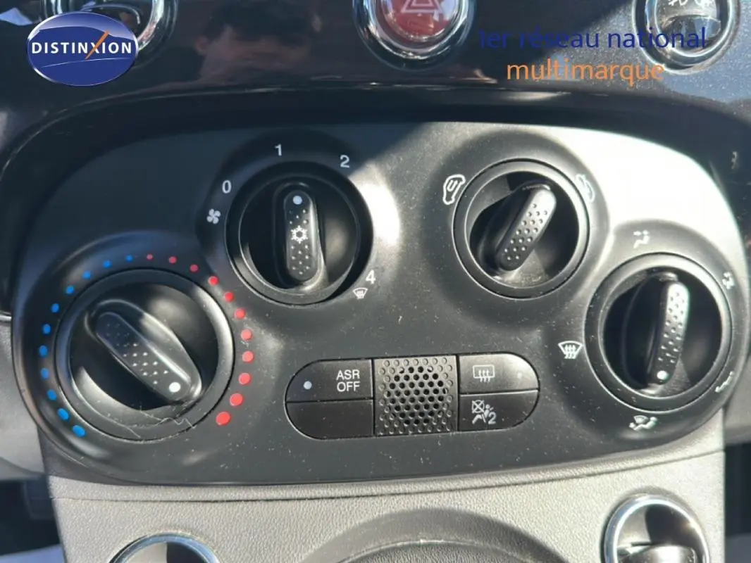 Gros plan sur la console de climatisation noire de la Fiat 500 noire, avec boutons de réglage et symbole ASR OFF.