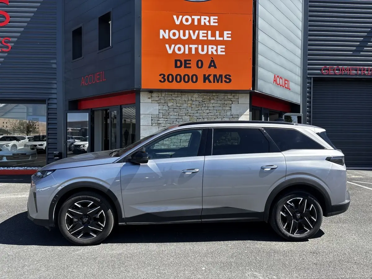 Profil côté gauche du Peugeot 5008 gris clair 2025, SUV hybride avec jantes noires et toit noir.