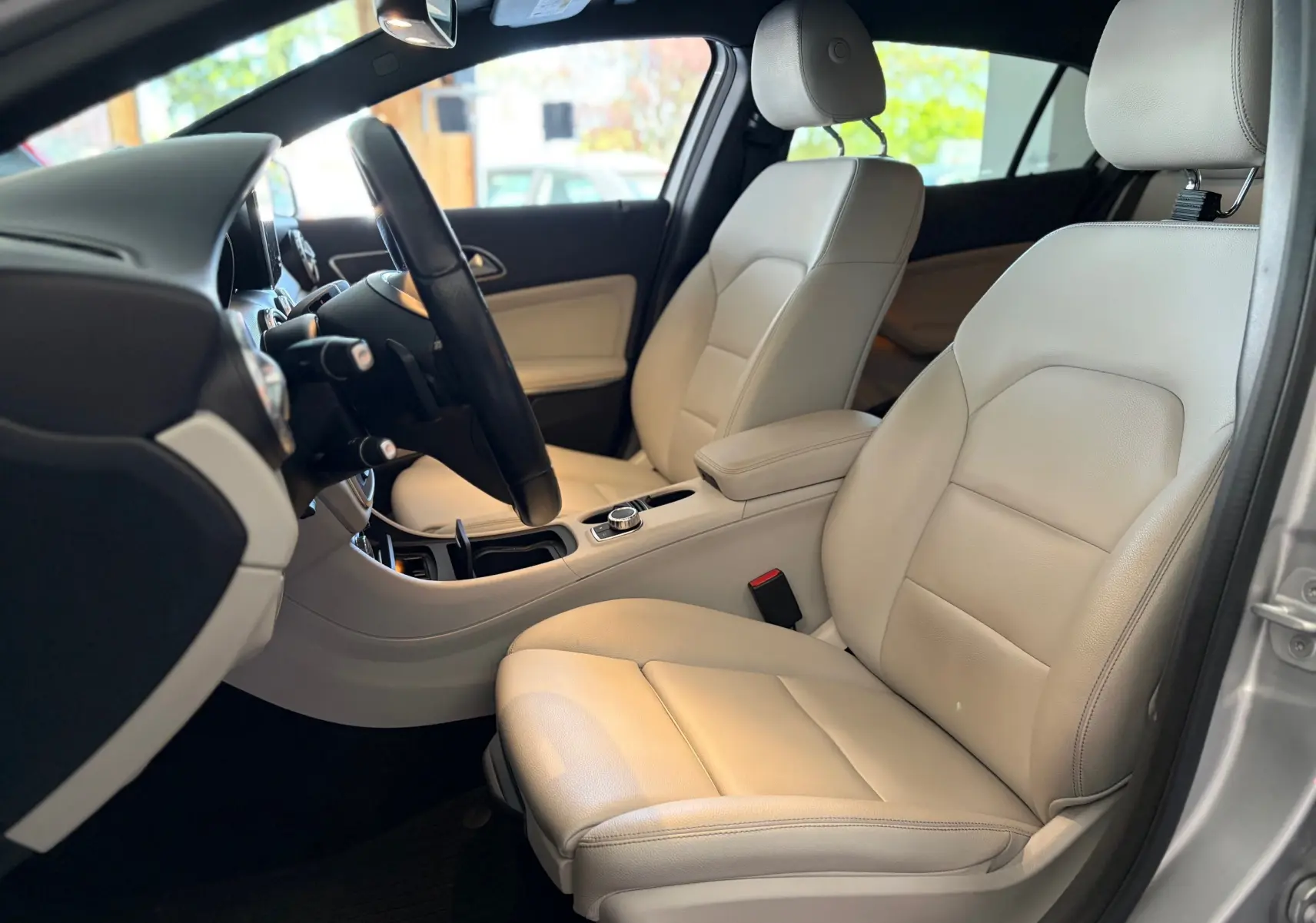 Vue intérieure côté conducteur du Mercedes GLA 200D Business 2015, sièges cuir beige et tableau de bord gris.