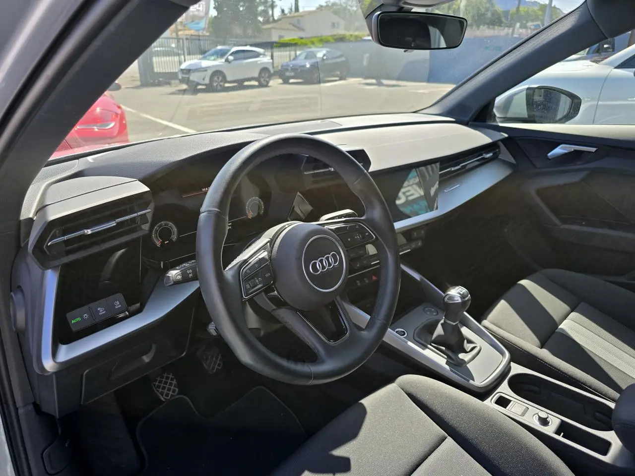Vue intérieure côté conducteur de l'Audi A3 Sportback 2022 avec volant cuir, boîte manuelle et tableau de bord moderne.
