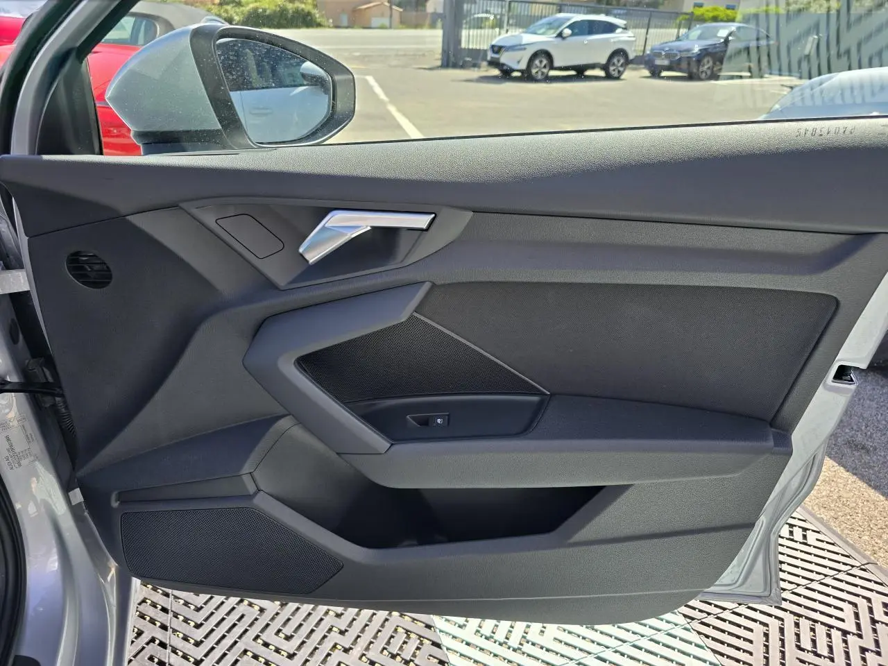 Vue de la porte avant gauche ouverte d’un Audi A3 Sportback gris argent, mettant en valeur la poignée et les haut-parleurs intégrés.