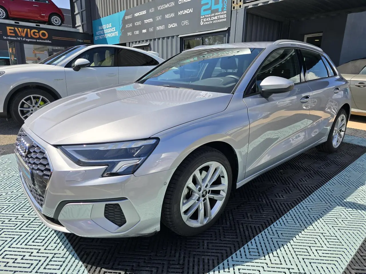 Audi A3 Sportback gris argent fleuret vue 3/4 avant droit, jantes alliage 17 pouces et phares LED visibles.